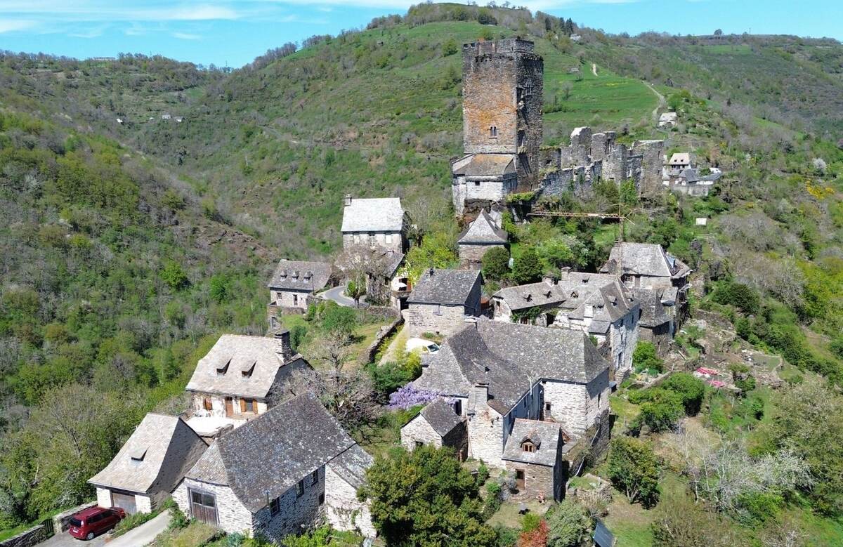Aerial view of Valon: stone houses with slate roofs and the castle tower, above the Truyère gorges