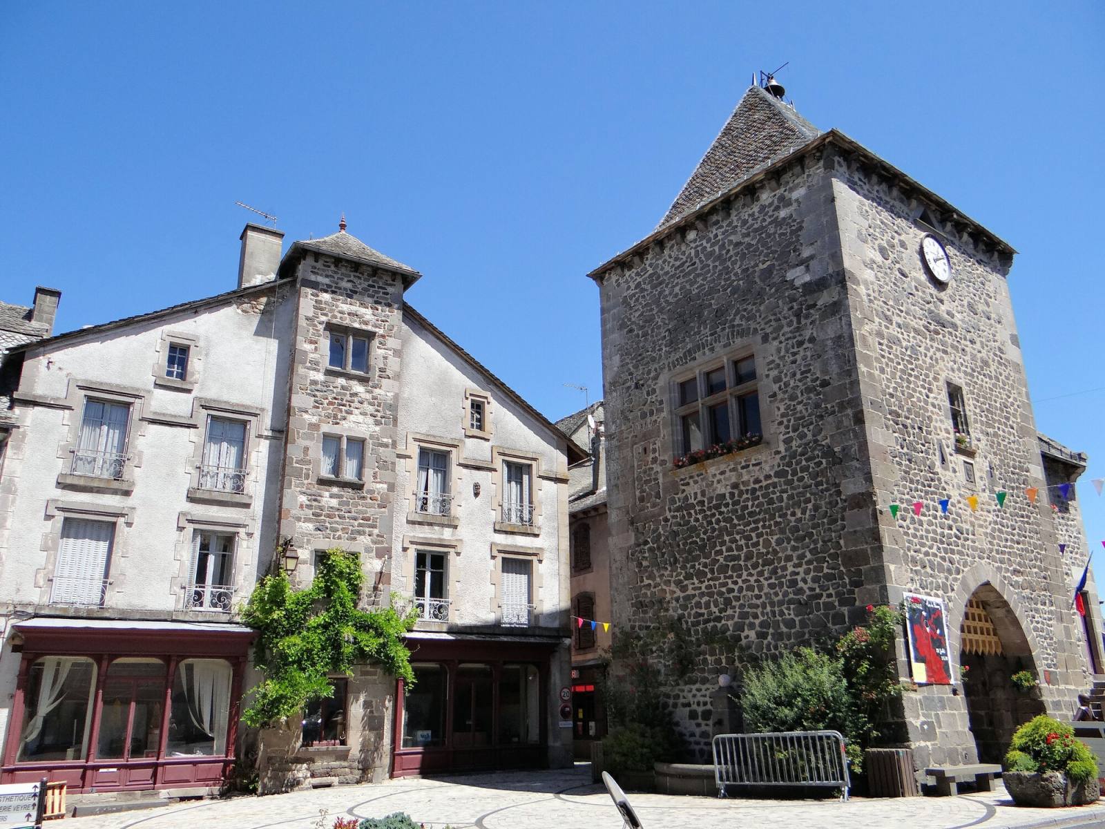 La tour de Monaco, porte de ville en basalte de Mur-de-Barrez, à côté d'une maison ancienne